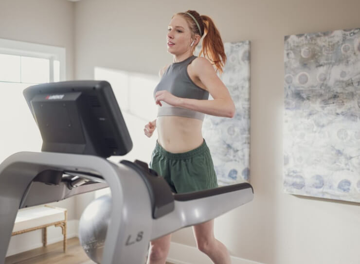 Woman running on treadmill and woman working out on elliptical in gym