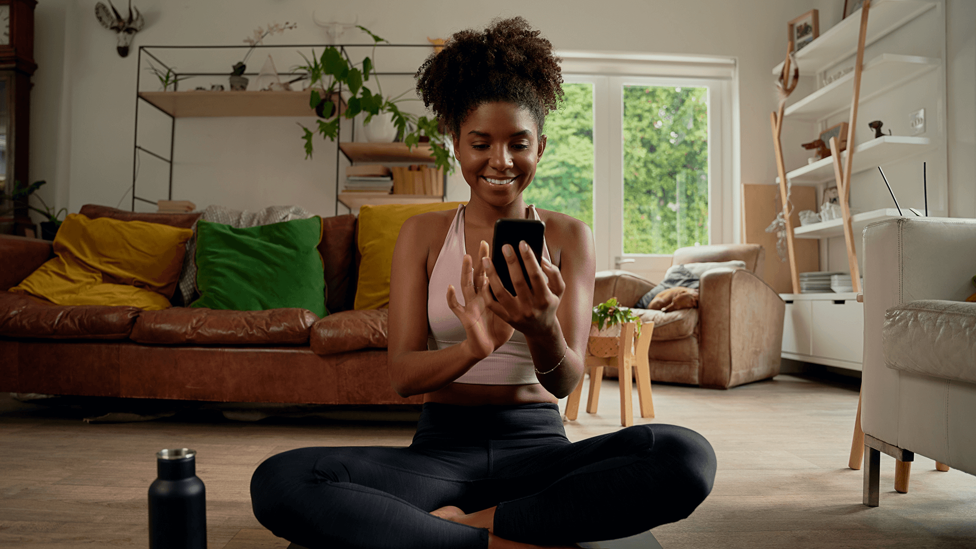 Woman on phone sitting on the floor after at-home workout