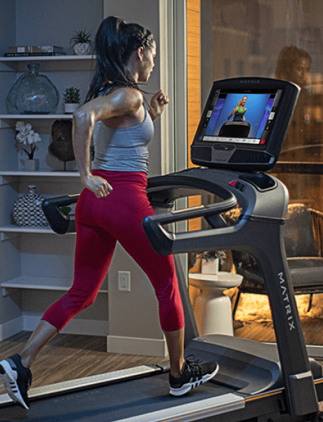 Woman running on Matrix treadmill using Treo app on treadmill console