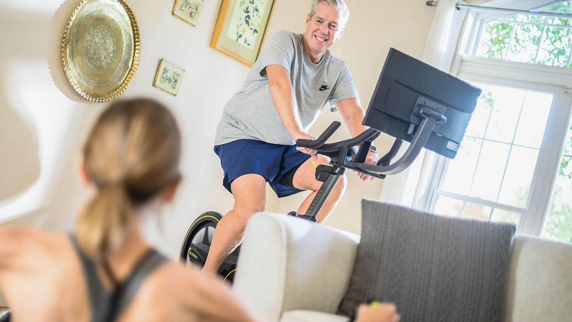 Man using Matrix upright bike with woman working out in foreground