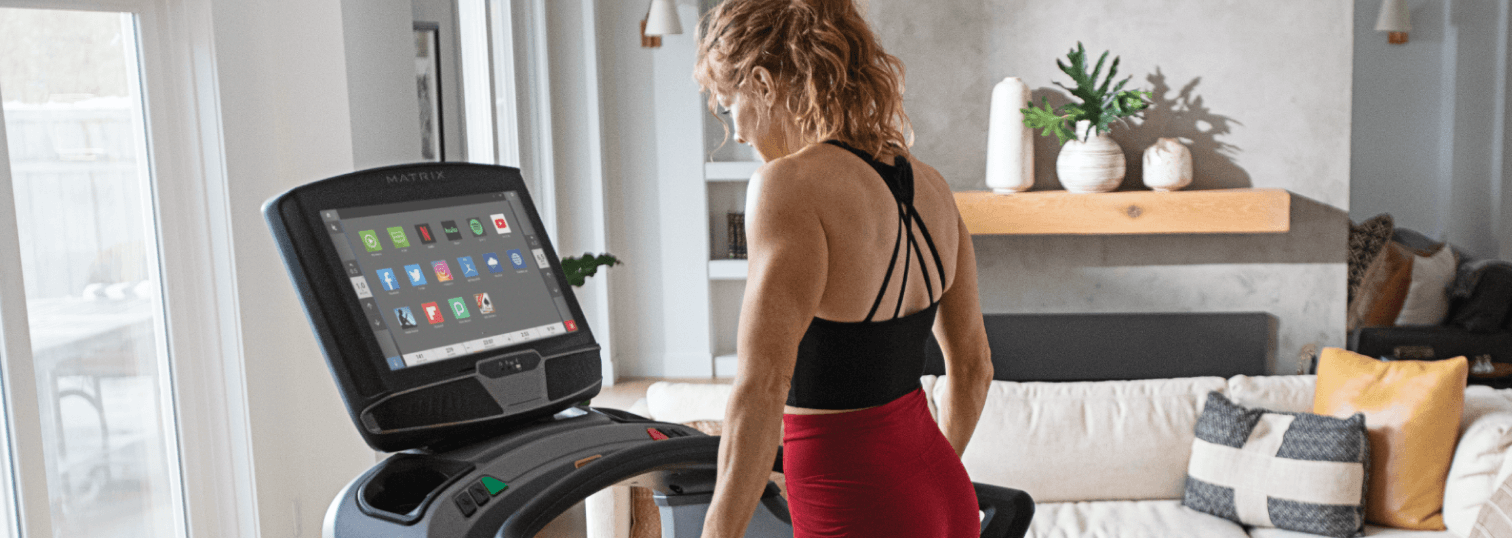 Woman standing on Matrix treadmill interacting with console