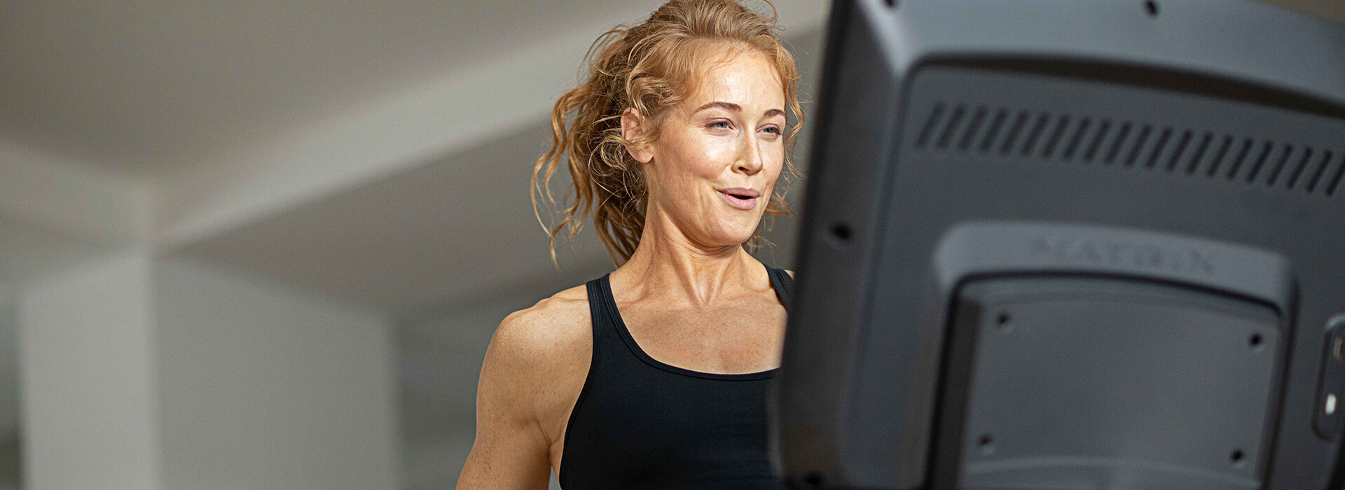 Woman standing on Matrix treadmill interacting with console